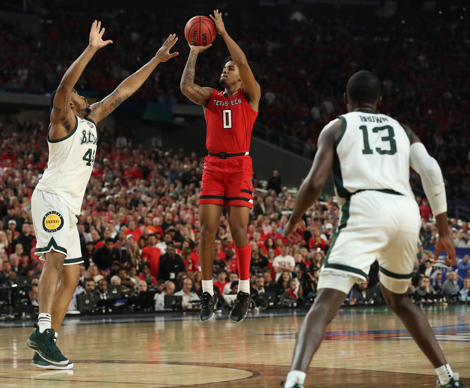Texas Tech's Kyler Edwards (0) shoots against Michigan State's Nick Ward (44) and Gabe Brown (13) during the first half in a semifinal of the NCAA Tournament Final Four on Saturday, April 6, 2019, at U.S. Bank Stadium in Minneapolis.